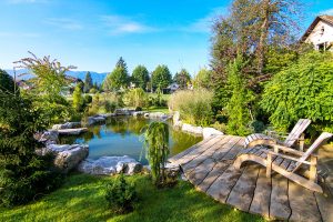 Two Adirondack chairs on a deck overlooking pond